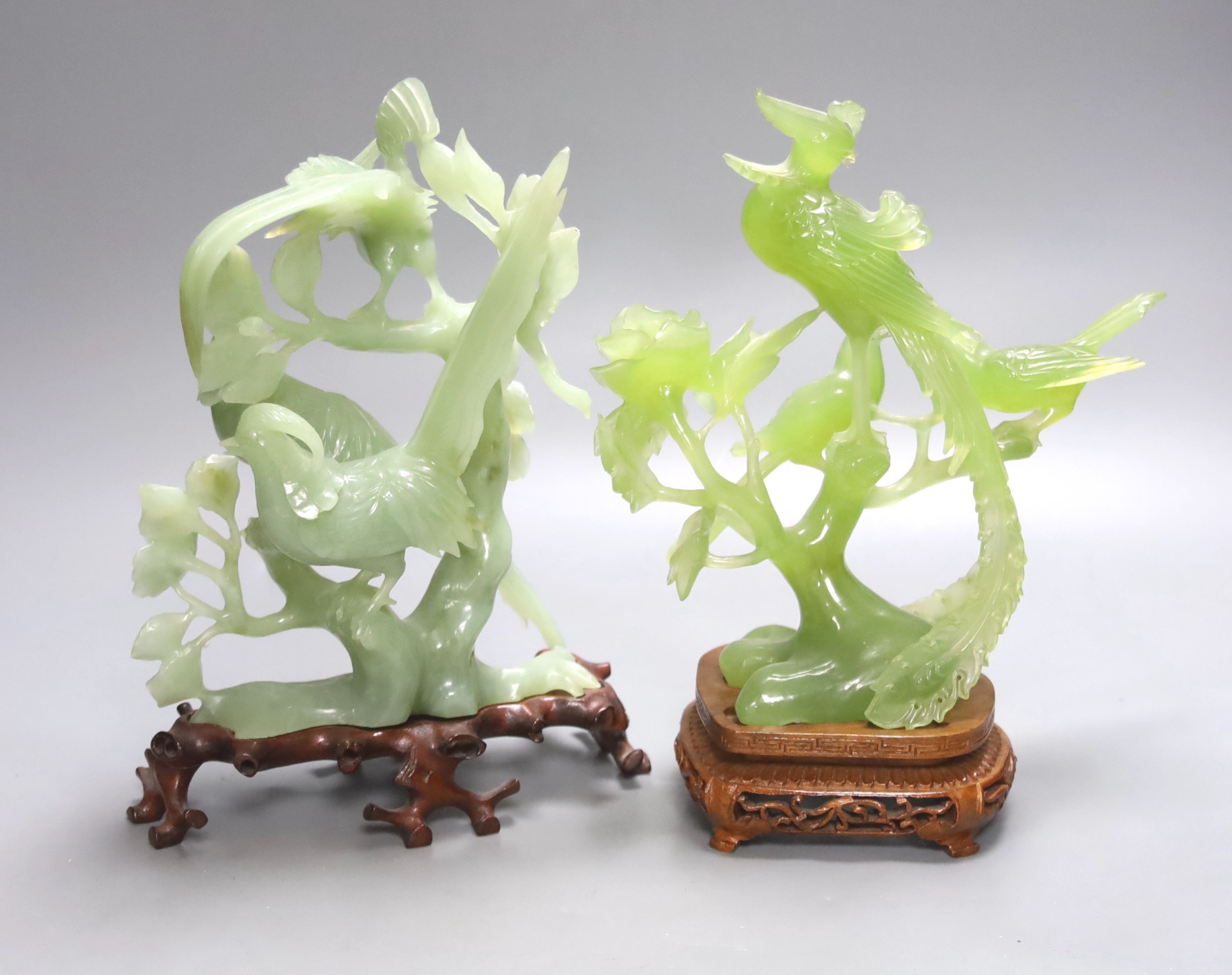 Two Chinese green bowenite jade carvings of exotic birds, H 28cm with carved wooden stands